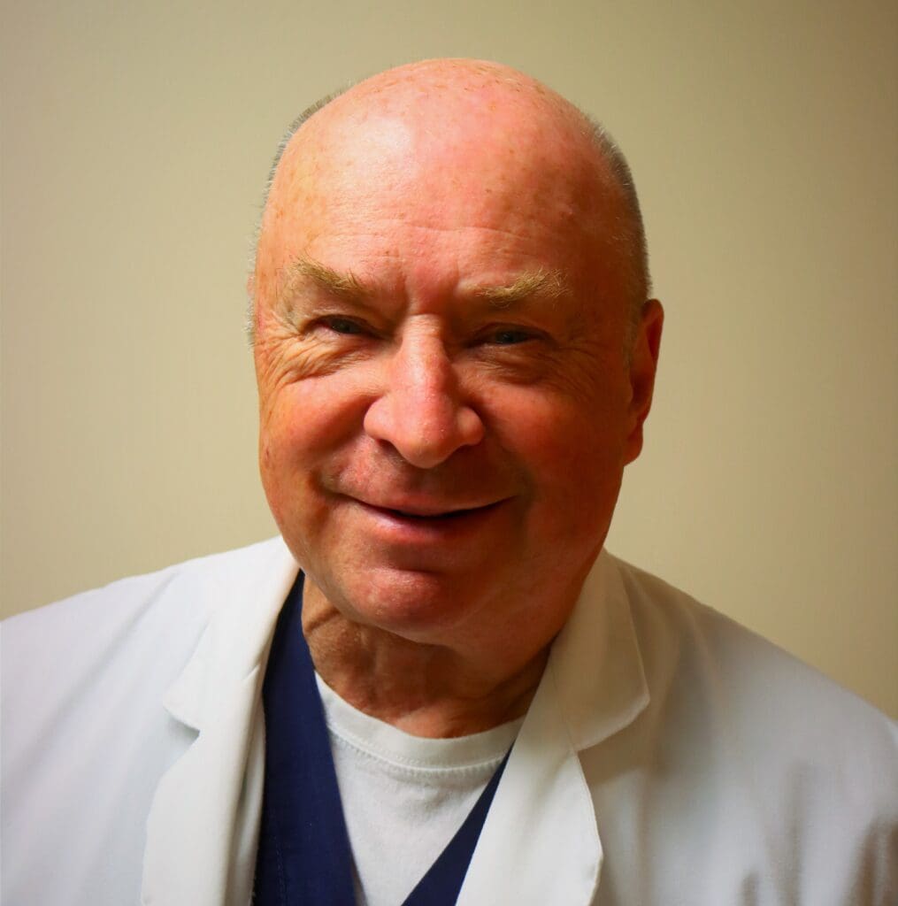 Smiling man in a white medical coat.