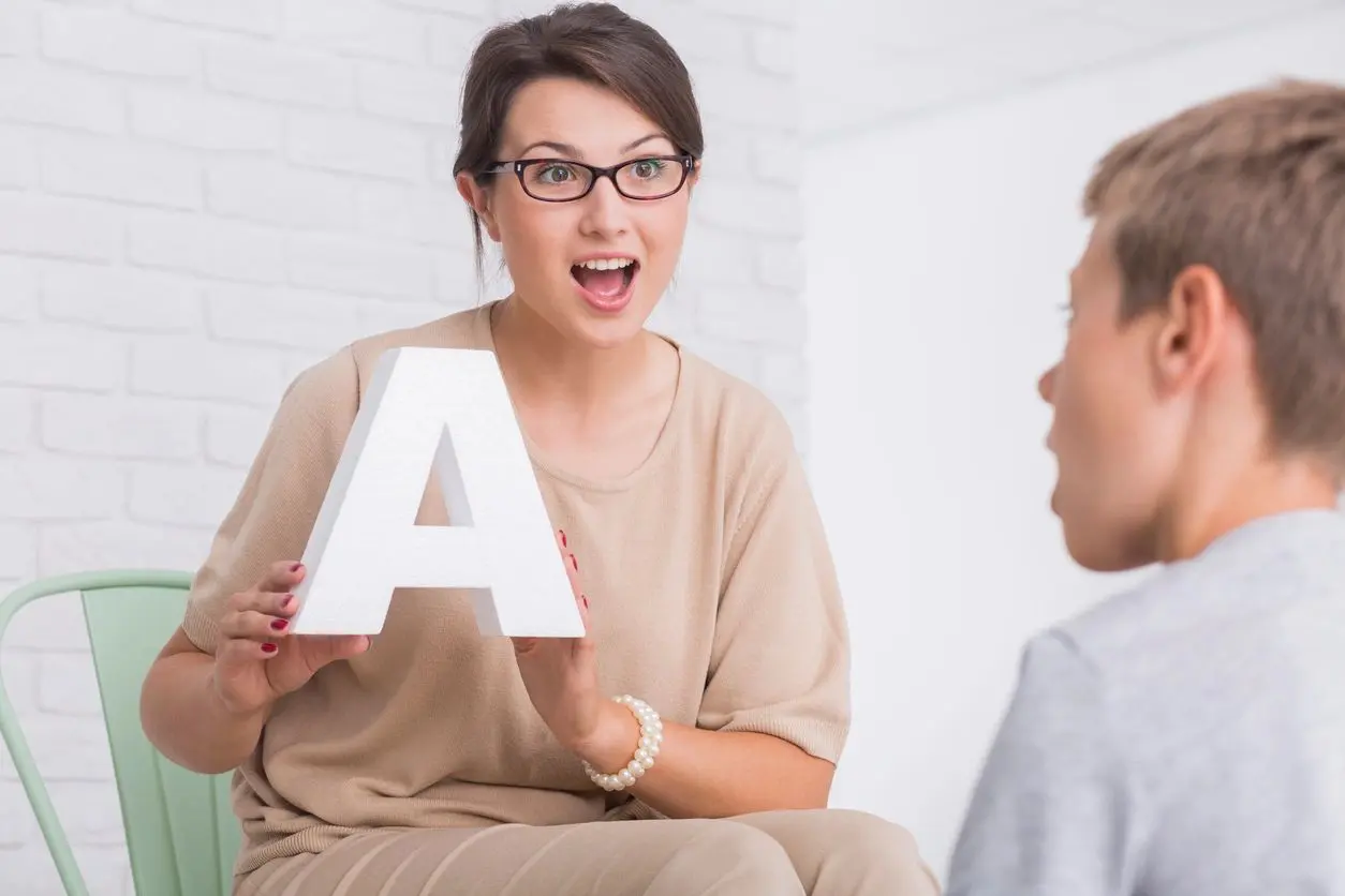 Woman teaching child with letter A.