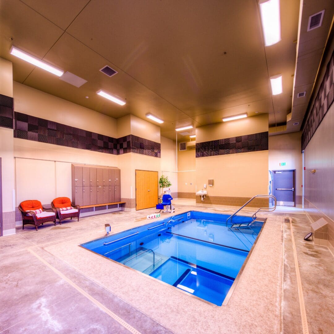 Indoor pool area with chairs and lockers.