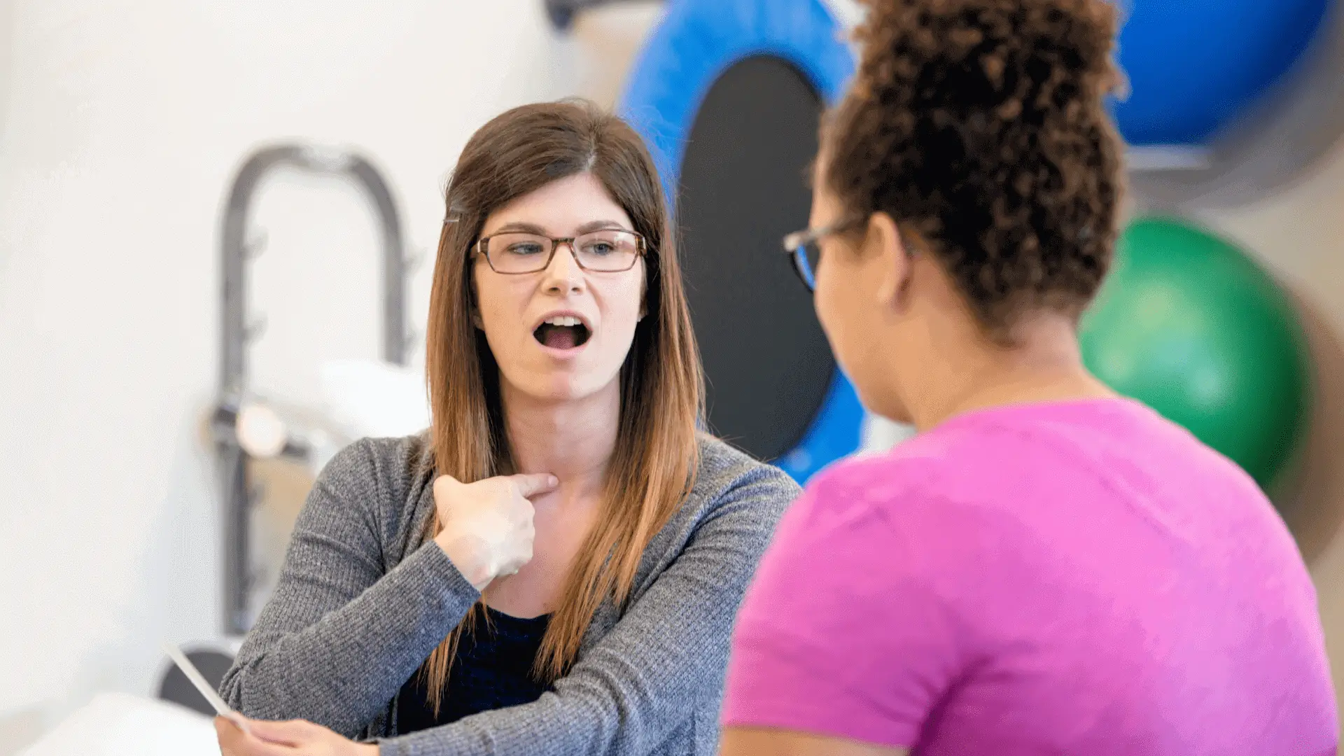 Woman practicing speech therapy with therapist.