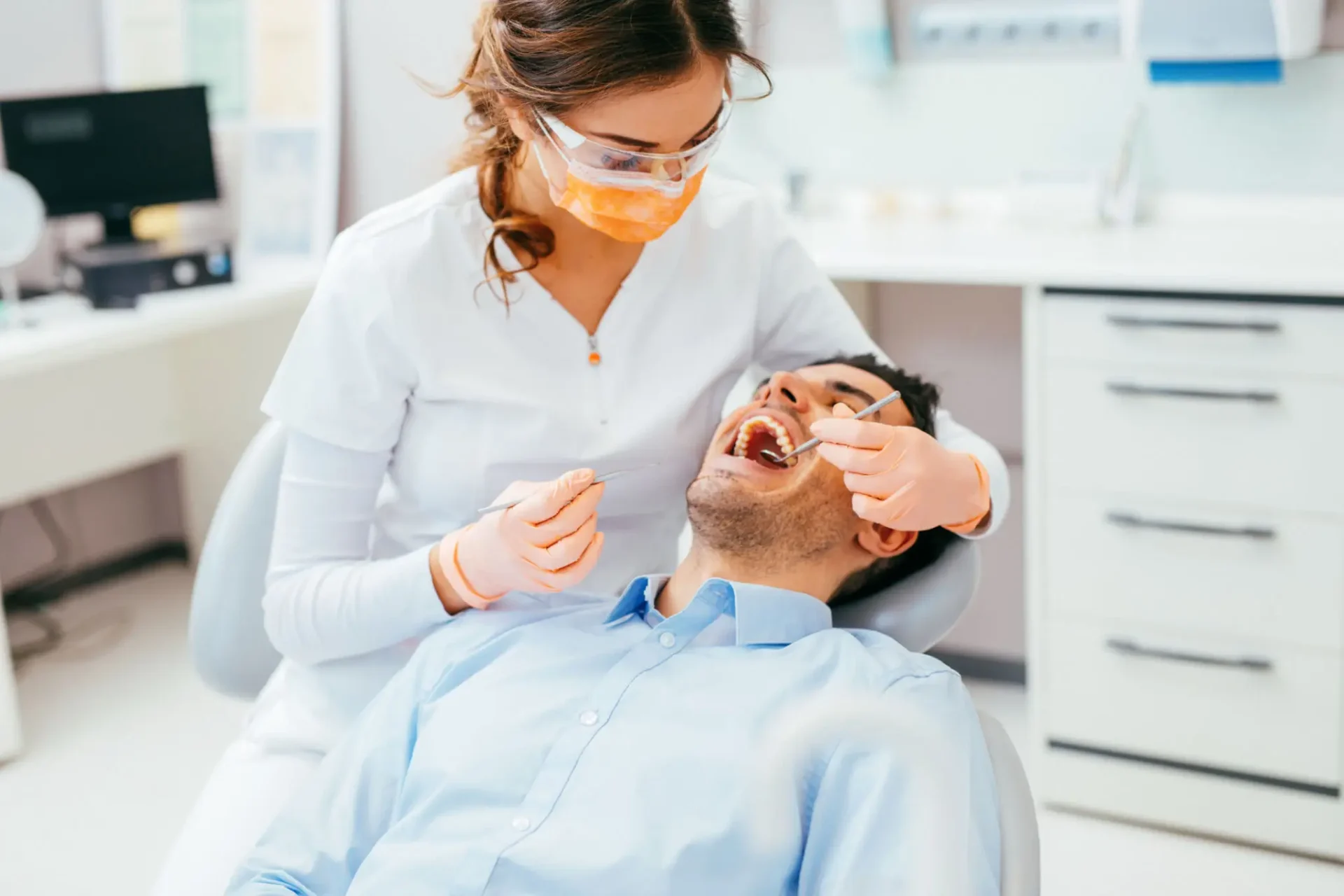 Dentist examining smiling patient in dental chair