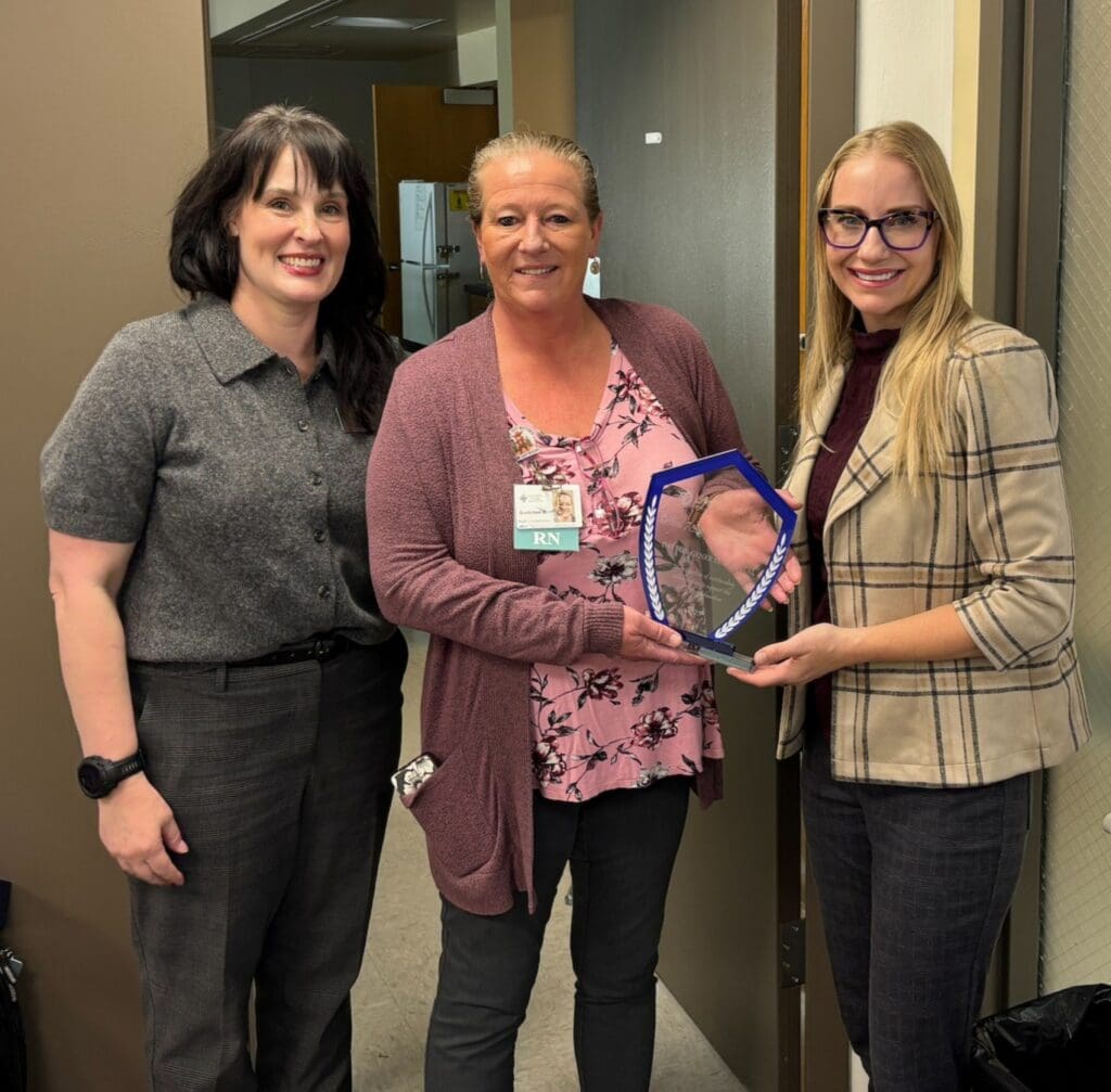 Three women standing with an award plaque.